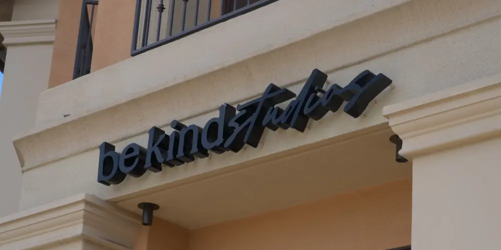 be kind studios script logo sign mounted above building entrance