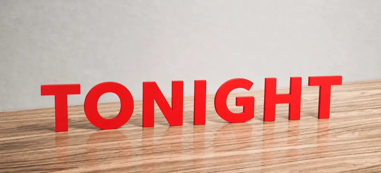 Red dimensional letters spelling TONIGHT standing on wooden table