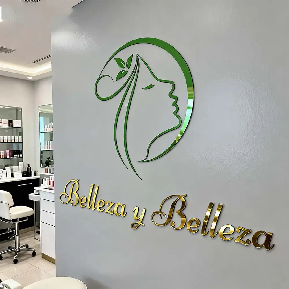 Green and gold mirror acrylic beauty salon logo mounted on a gray wall