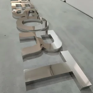 Polished mirror chrome dimensional letters laid on concrete floor at an angle