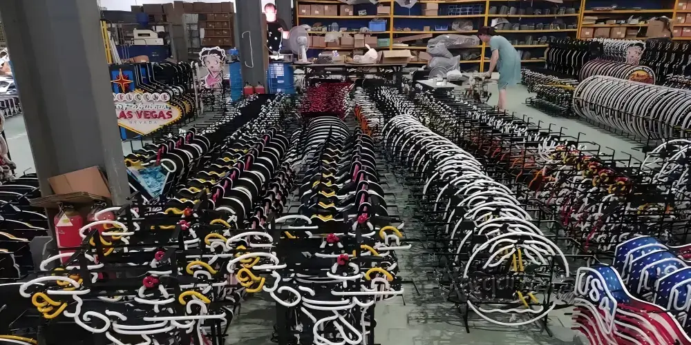 Rows of glass neon signs arranged on metal frames in a production workshop