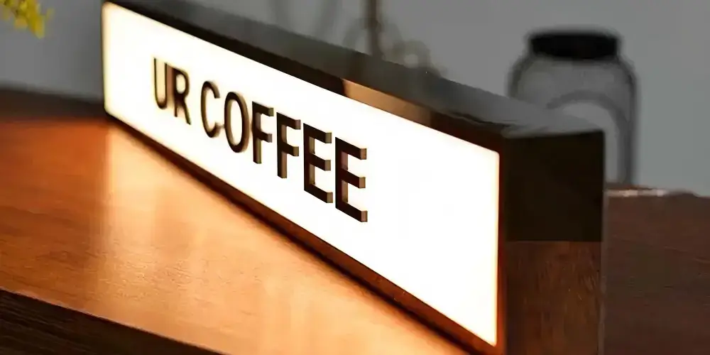 Raised black acrylic letters spell “James Kelleher Lawyers” in a layered typographic arrangement, with polished faces and visible depth against a cream-colored wall.