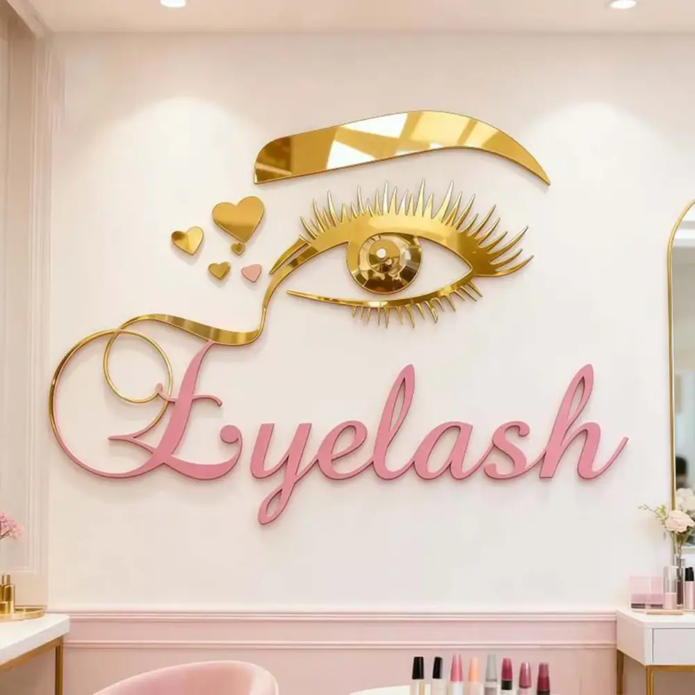 Gold mirror acrylic eye graphic and pink Eyelash lettering mounted on a salon wall