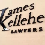 Glossy black James Kelleher Lawyers acrylic letters mounted on a cream wall