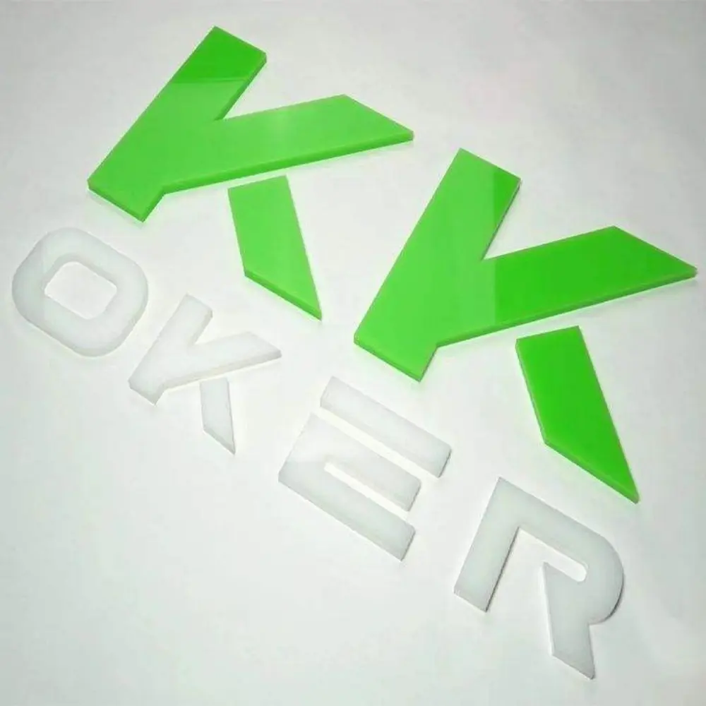 Green and white cut acrylic logo components arranged on a light surface