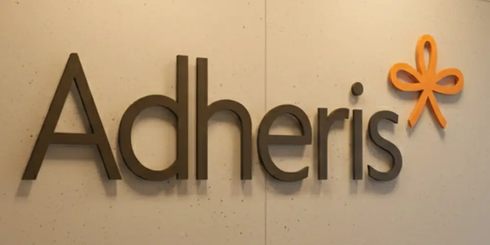Dark Adheris acrylic letters with an orange bow logo mounted on a beige wall