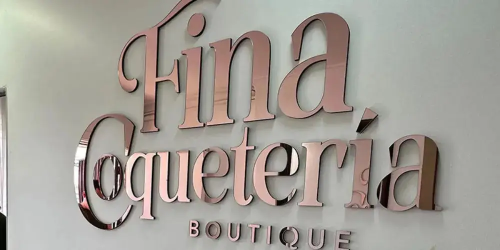 Rose-gold mirror acrylic boutique letters mounted on a light-colored wall