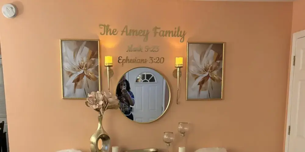 Gold mirror acrylic family name and date lettering arranged above a round wall mirror