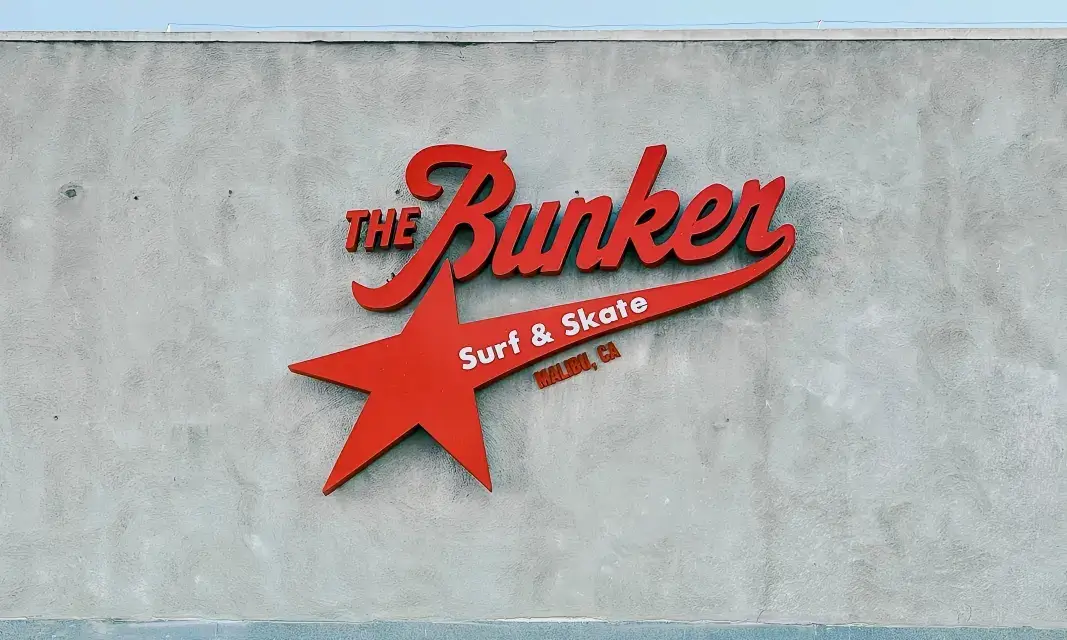 Red acrylic channel letter sign for The Bunker Surf & Skate mounted on textured concrete wall
