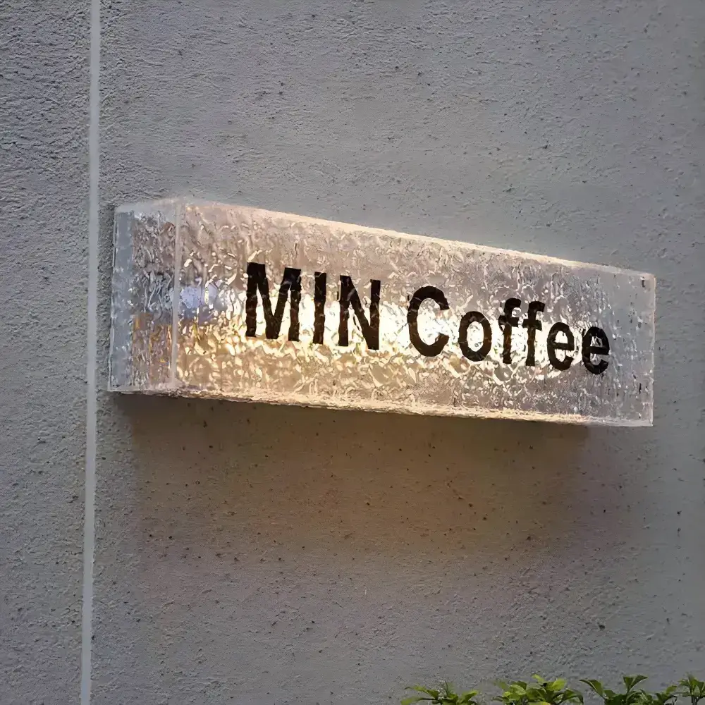 Wall-mounted illuminated acrylic light box with a textured clear face and MIN Coffee lettering