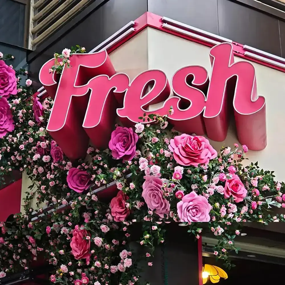 Large pink Fresh letters above a flower-covered storefront