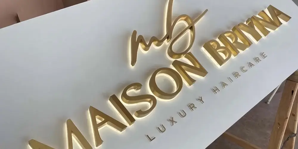Brass backlit Maison Brittani letters with warm halo illumination