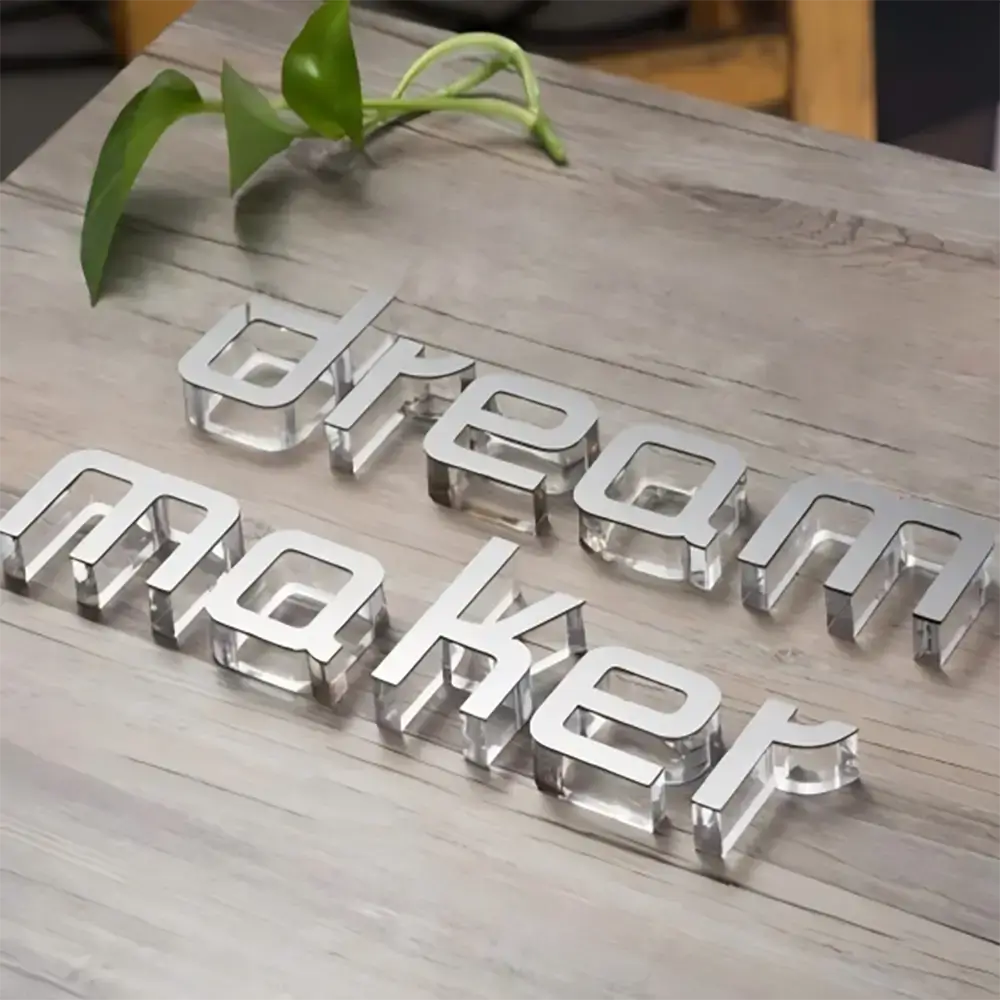 Clear acrylic dream maker letters with silver faces arranged on a wooden tabletop