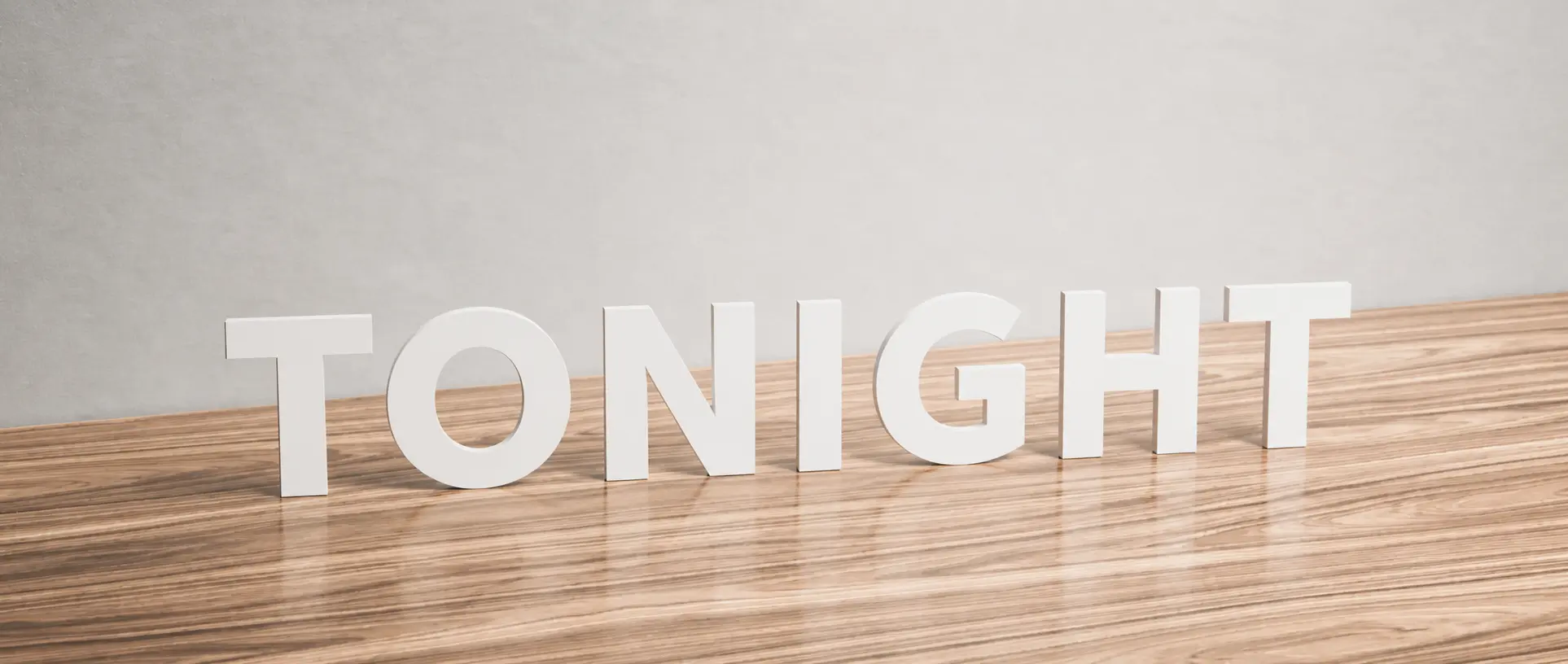 Freestanding white acrylic letters spelling TONIGHT on a wooden tabletop