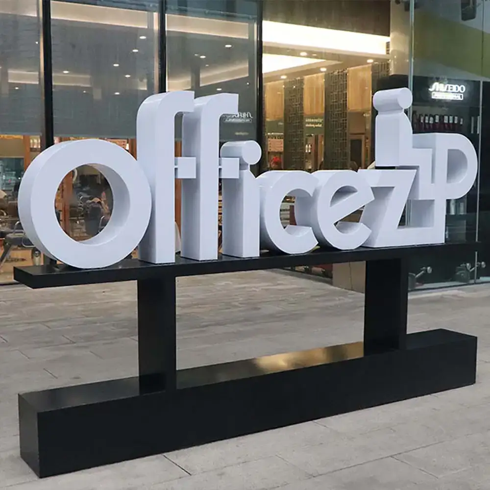 White freestanding channel letters spelling "Officezip" mounted on a custom black base outside a storefront