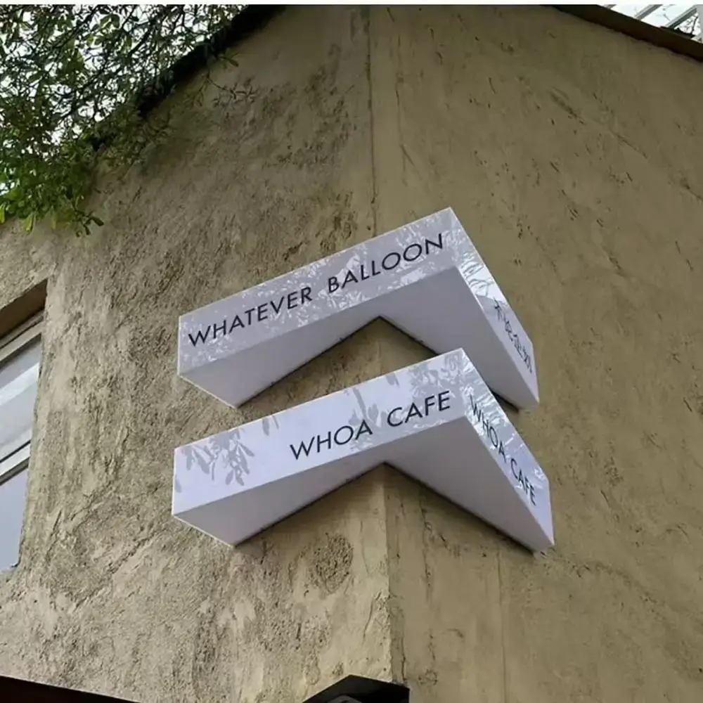 Two custom chevron-shaped projecting light boxes mounted on an exterior café wall