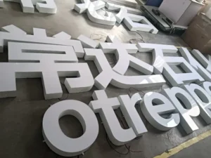 White glossy dimensional letters spelling Chinese characters and "Otreppo" laid on factory floor