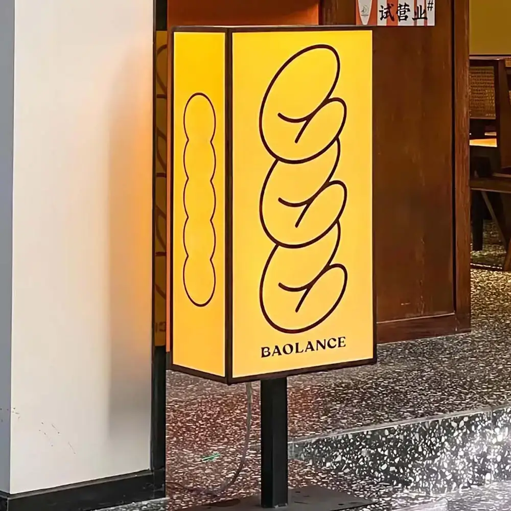 Freestanding rectangular light box with warm yellow illuminated graphics