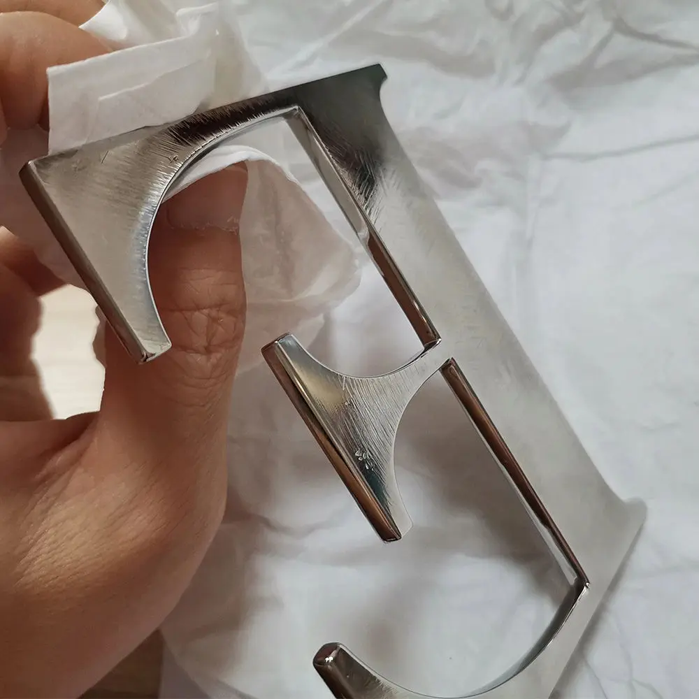 Hand holding polished chrome letter with mirror finish close-up