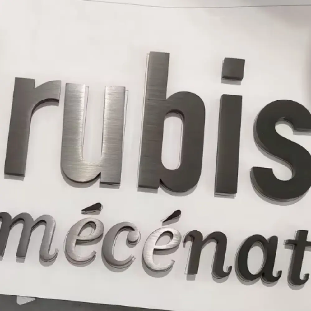 Brushed metal dimensional letters spelling "rubis mécénat" close-up