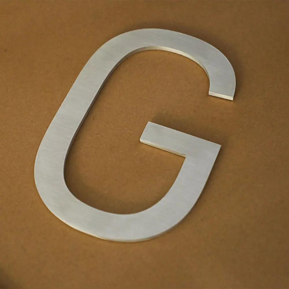 Brushed stainless steel dimensional letter G on brown background
