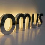 OMNUS brushed metal dimensional letters with warm halo-lit backlighting, close-up side view