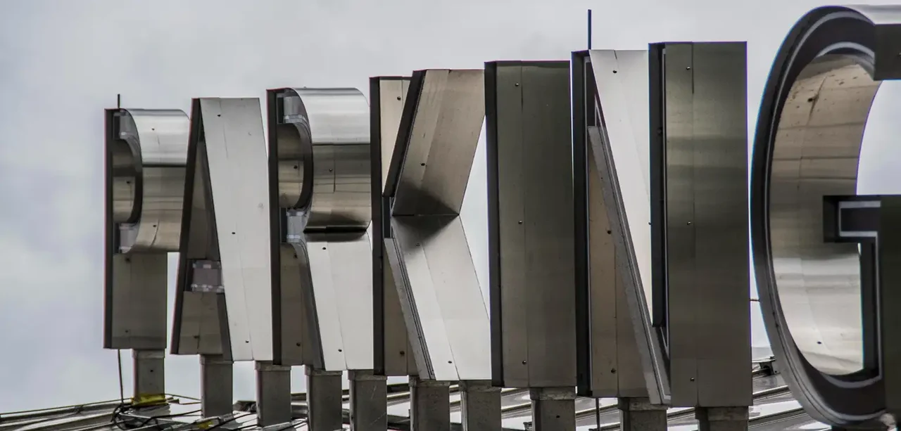 Close-up of unfinished raw metal channel letters showing internal structure against overcast sky