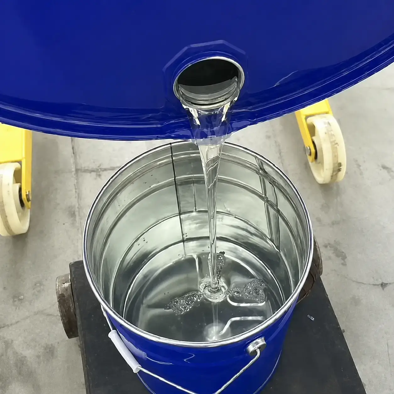 Clear casting resin poured from a drum into a metal container