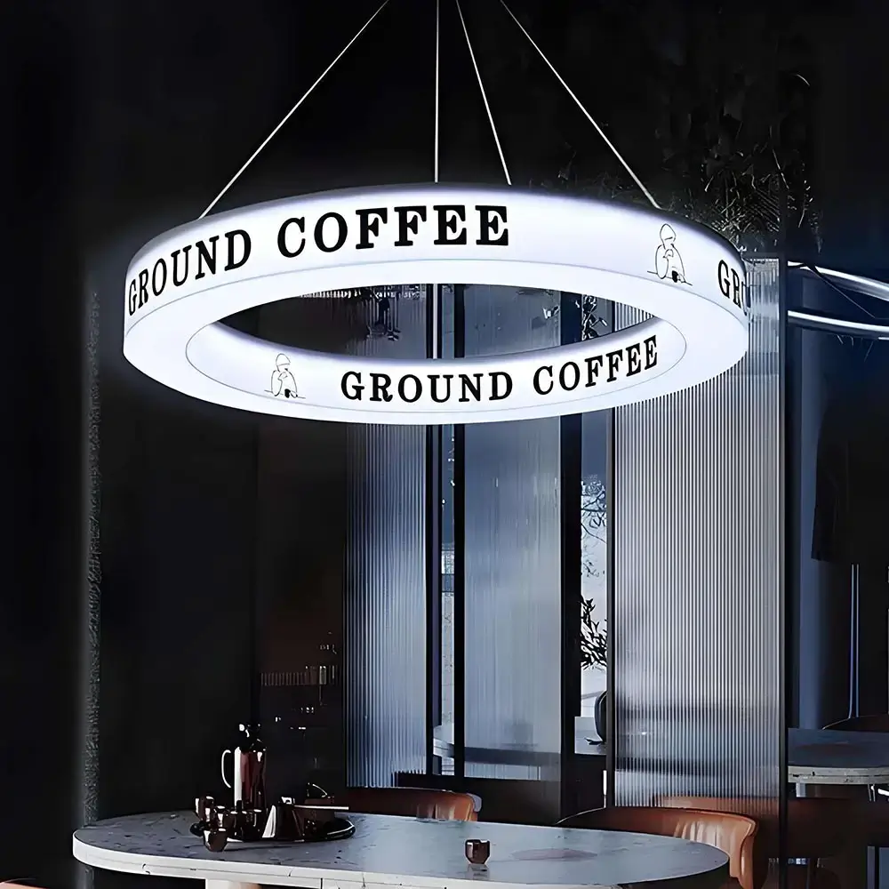 Ceiling-suspended illuminated ring light box displaying Ground Coffee branding