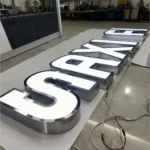 Stainless steel trim front-lit channel letters illuminated in a workshop