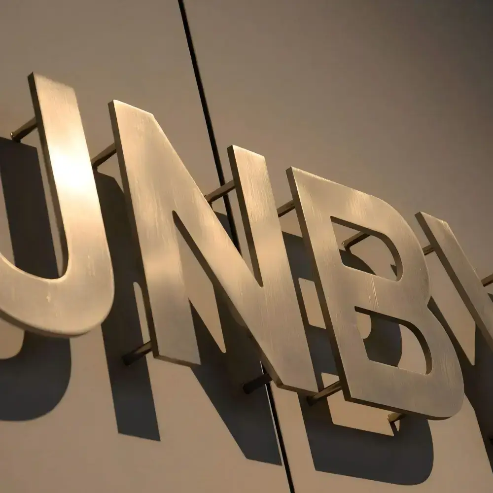 Gold metal letters mounted on a wall with visible standoff studs creating a shadow-gap effect