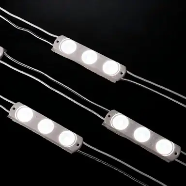 Triple-lens LED sign modules connected by wires on a black background