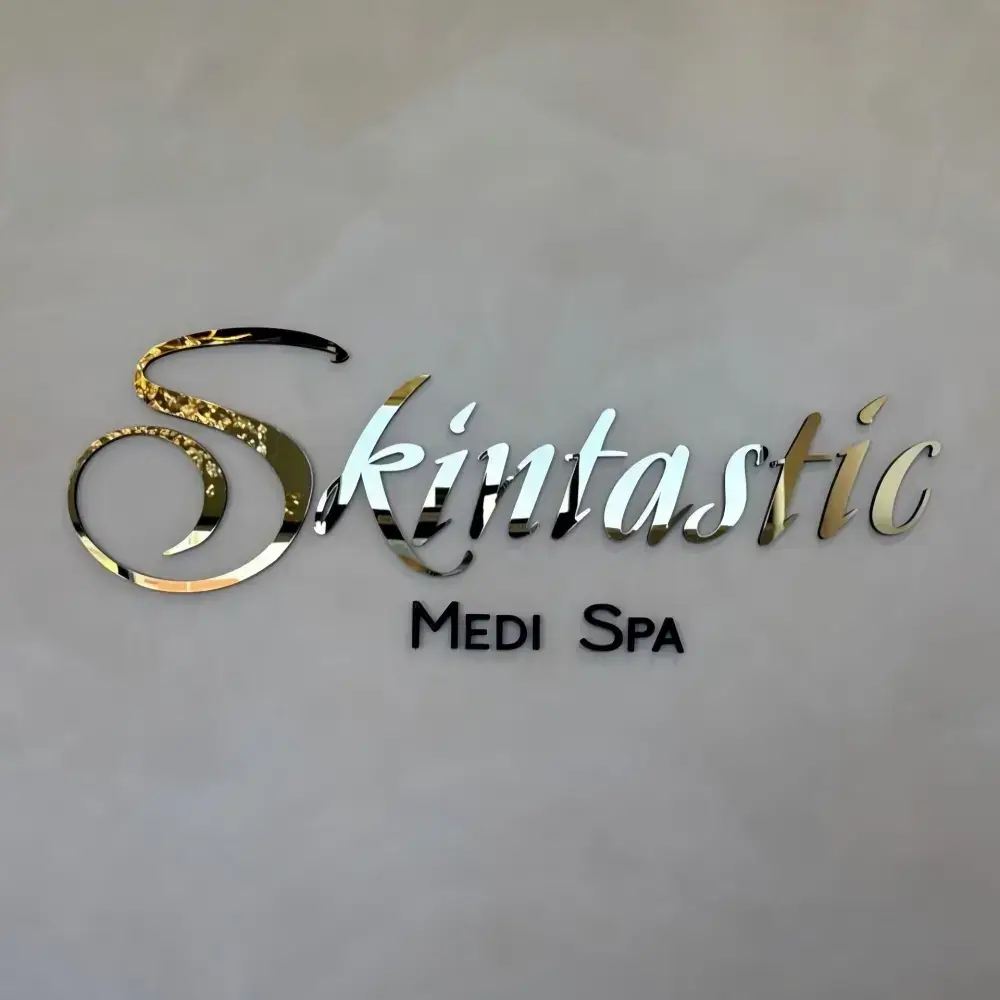 Reflective Skintastic Medi Spa acrylic logo with black lettering on a light wall