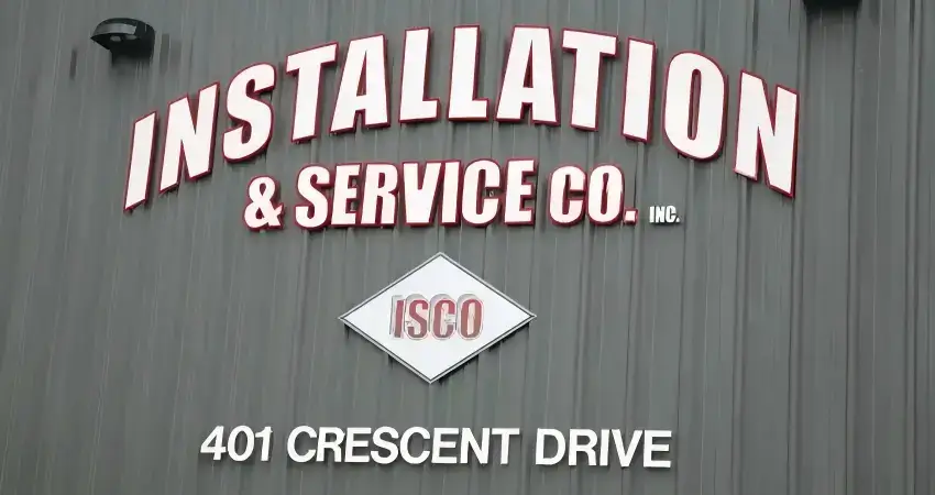 White laser-cut acrylic Installation and Service Co letters mounted on a gray exterior wall