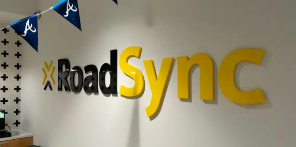 RoadSync yellow and black dimensional lettering on office wall