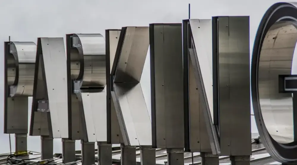 Close-up of unfinished raw metal channel letters showing internal structure against overcast sky